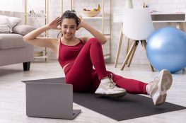 девушка занимается дома фитнесом перед ноутбуком с открытым сайтом с виртуальным хостингом